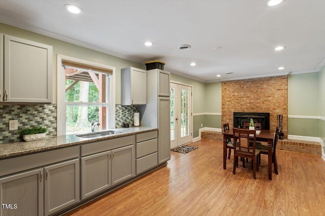 1109 Buckingham Rd, Garner, NC 27529 - kitchen with a sink, gray cabinetry, crown molding, tasteful backsplash, and light wood-type flooring