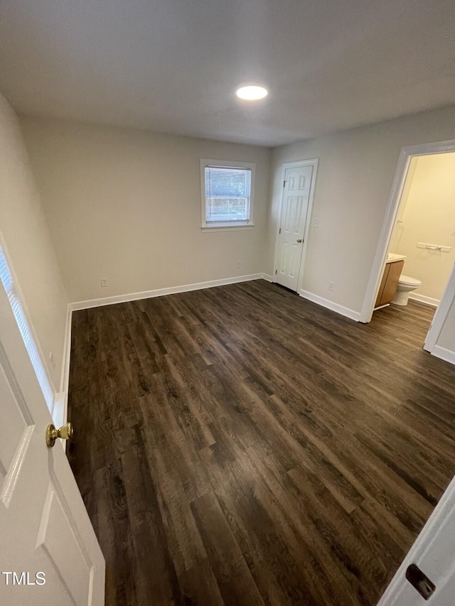3522 Ivy Commons Dr Unit 101, Raleigh, NC 27606 - unfurnished bedroom with dark wood-style floors, baseboards, and connected bathroom