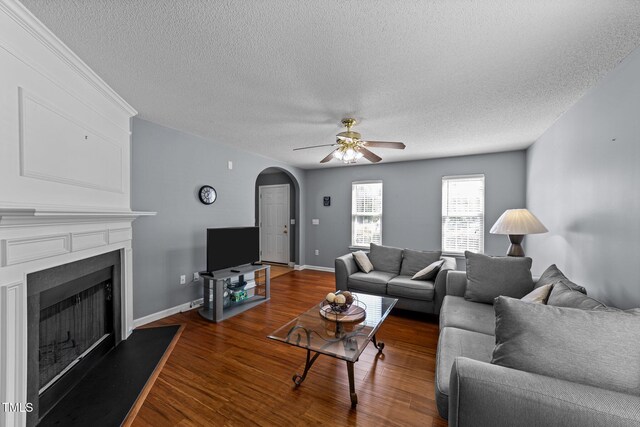 4221 Ivy Hill Rd, Raleigh, NC 27616 - living area featuring arched walkways, a textured ceiling, a fireplace with raised hearth, wood finished floors, and a ceiling fan