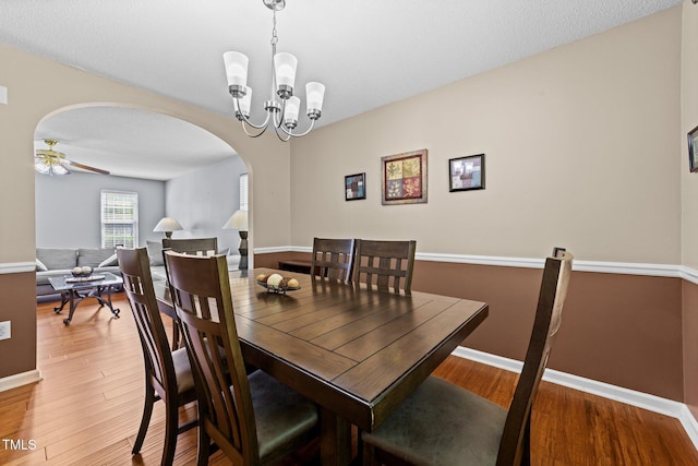 4221 Ivy Hill Rd, Raleigh, NC 27616 - dining room featuring arched walkways, baseboards, light wood-style floors, a chandelier, and a ceiling fan