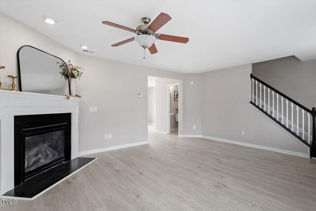 197 Scranton Ct, Cameron, NC 28326 - unfurnished living room featuring stairway, wood finished floors, ceiling fan, a glass covered fireplace, and baseboards