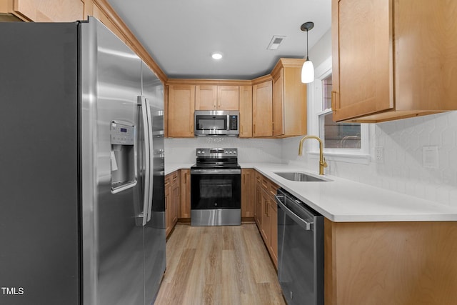 708 Powell Dr Unit B, Raleigh, NC 27606 - kitchen with appliances with stainless steel finishes, a sink, light wood-style flooring, light countertops, and pendant lighting
