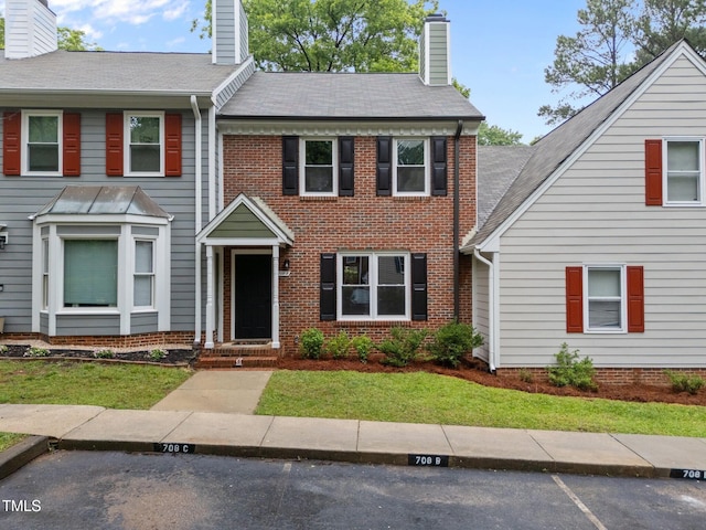 708 Powell Dr Unit B, Raleigh, NC 27606 - view of front of property featuring a chimney, uncovered parking, a front yard, and brick siding