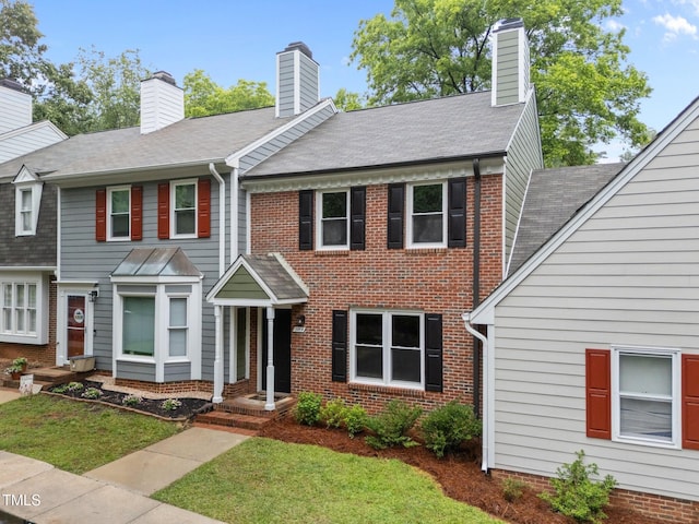 708 Powell Dr Unit B, Raleigh, NC 27606 - view of front of house with a chimney, a front yard, and brick siding