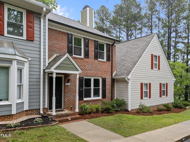 708 Powell Dr Unit B, Raleigh, NC 27606 - view of front of house with a chimney, brick siding, a front yard, and roof with shingles