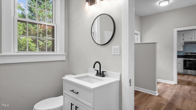 830 S Chestnut St, Henderson, NC 27536 - bathroom with wood finished floors, vanity, toilet, baseboards, and backsplash