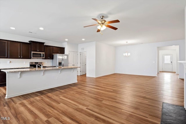 346 E Painted Way, Clayton, NC 27527 - kitchen with appliances with stainless steel finishes, ceiling fan, a kitchen breakfast bar, dark brown cabinets, and backsplash