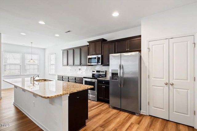 346 E Painted Way, Clayton, NC 27527 - kitchen with stainless steel appliances, backsplash, light stone counters, light wood-style floors, and dark brown cabinetry
