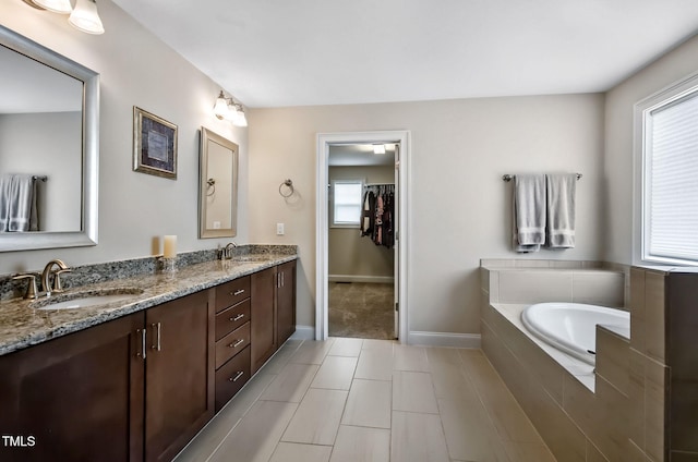 2100 Della Ct, Apex, NC 27502 - bathroom with double vanity, a garden tub, baseboards, a spacious closet, and tile patterned flooring