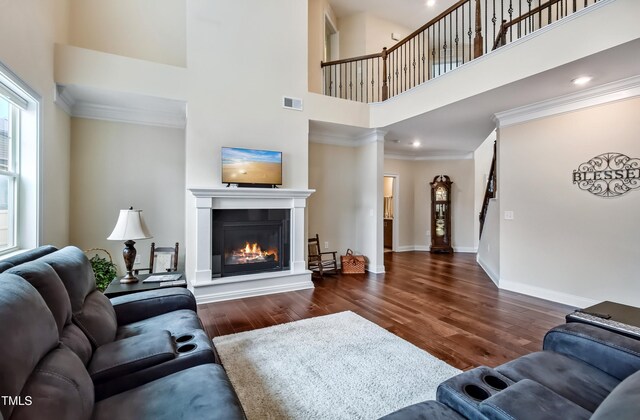 2100 Della Ct, Apex, NC 27502 - living area featuring a high ceiling, wood finished floors, a glass covered fireplace, baseboards, and crown molding