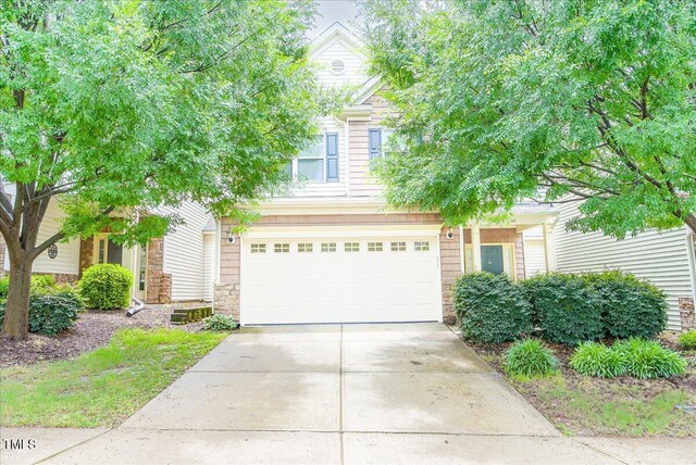 145 Torrey Heights Ln, Durham, NC 27703 - view of property hidden behind natural elements with stone siding, concrete driveway, and a garage