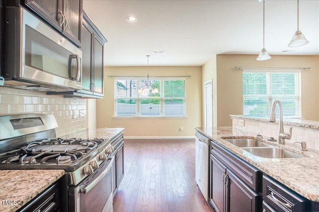 145 Torrey Heights Ln, Durham, NC 27703 - kitchen featuring stainless steel appliances, a sink, decorative backsplash, light stone countertops, and baseboards