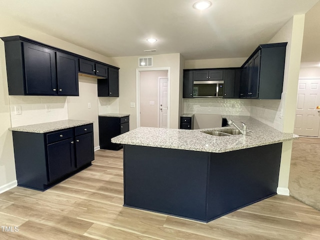 226 Bonsai Way, Four Oaks, NC 27524 - kitchen featuring stainless steel microwave, a peninsula, light wood-style flooring, decorative backsplash, and recessed lighting