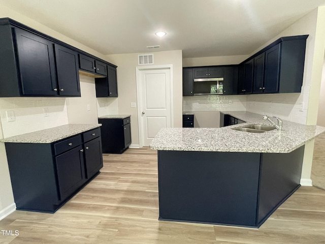 226 Bonsai Way, Four Oaks, NC 27524 - kitchen featuring stainless steel microwave, a peninsula, tasteful backsplash, light wood finished floors, and recessed lighting