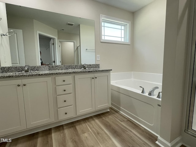 226 Bonsai Way, Four Oaks, NC 27524 - bathroom with double vanity, wood finished floors, a bath, an enclosed shower, and a walk in closet