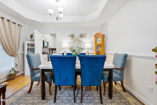 4705 Royal Troon Dr, Raleigh, NC 27604 - dining area featuring a chandelier, a raised ceiling, wood finished floors, and baseboards