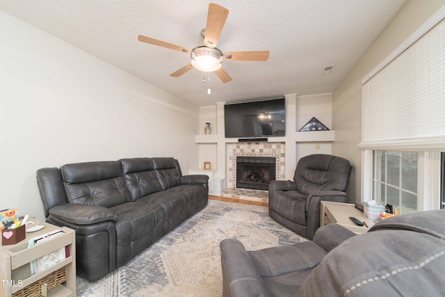 4710 Rollingwood Dr, Durham, NC 27713 - living area with ceiling fan, a tiled fireplace, a textured ceiling, and wood finished floors