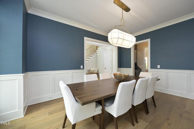 7736 Roberts Rd, Apex, NC 27523 - dining area with stairs, light wood-style floors, a wainscoted wall, ornamental molding, and a decorative wall