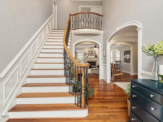 2207 Cameron Pond Dr, Cary, NC 27519 - staircase with a towering ceiling, a fireplace, wood finished floors, and arched walkways