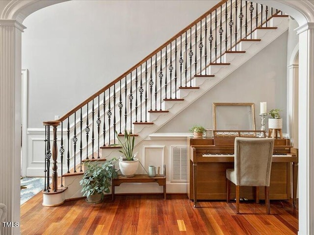 2207 Cameron Pond Dr, Cary, NC 27519 - stairs with arched walkways, a decorative wall, wood finished floors, decorative columns, and a wainscoted wall
