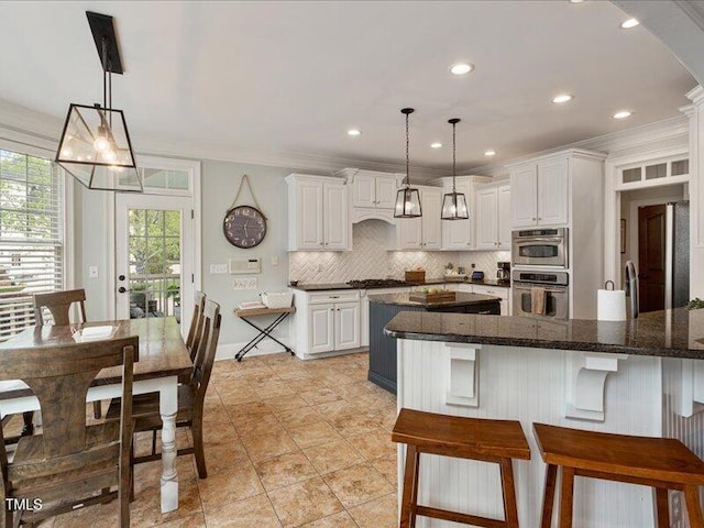 2207 Cameron Pond Dr, Cary, NC 27519 - kitchen featuring decorative backsplash, a kitchen breakfast bar, white cabinetry, crown molding, and recessed lighting