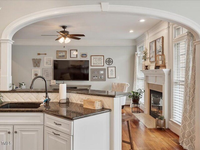 2207 Cameron Pond Dr, Cary, NC 27519 - kitchen featuring a sink, arched walkways, ceiling fan, white cabinetry, and dark stone countertops