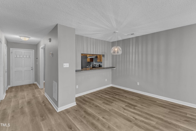 4658 Fawnbrook Cir, Raleigh, NC 27612 - unfurnished living room with a textured ceiling, wood finished floors, baseboards, and a chandelier