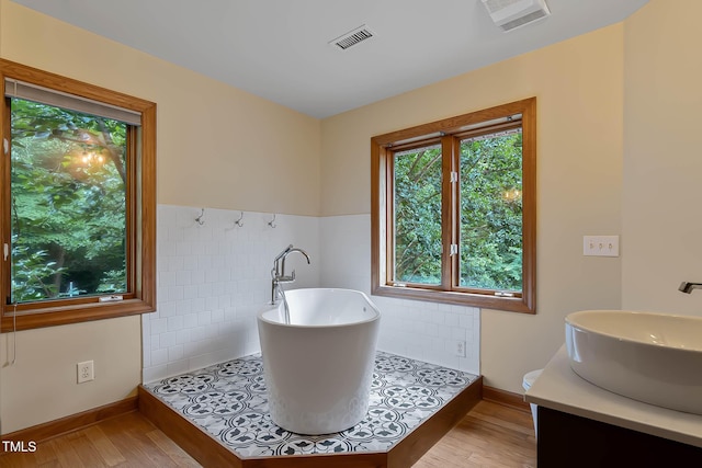 145 Ryan Rd, Pittsboro, NC 27312 - full bath featuring tile walls, a freestanding bath, wood finished floors, wainscoting, and vanity