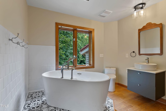 145 Ryan Rd, Pittsboro, NC 27312 - full bathroom featuring tile walls, vanity, a freestanding bath, wood finished floors, and toilet