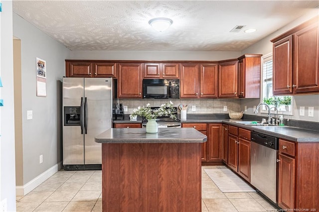 191 Trenton Pl, Cameron, NC 28326 - kitchen featuring stainless steel appliances, a sink, dark countertops, light tile patterned floors, and a center island
