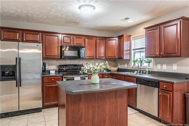 191 Trenton Pl, Cameron, NC 28326 - kitchen with stainless steel appliances, a sink, dark countertops, light tile patterned floors, and a center island