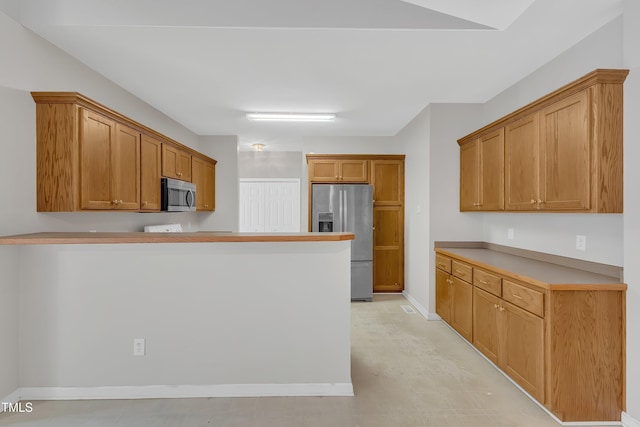103 Kylie Savannah Ct, Cary, NC 27511 - kitchen with appliances with stainless steel finishes, a peninsula, brown cabinets, baseboards, and light countertops