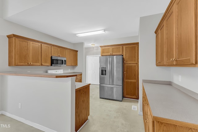 103 Kylie Savannah Ct, Cary, NC 27511 - kitchen featuring stainless steel appliances, brown cabinetry, light floors, a peninsula, and light countertops