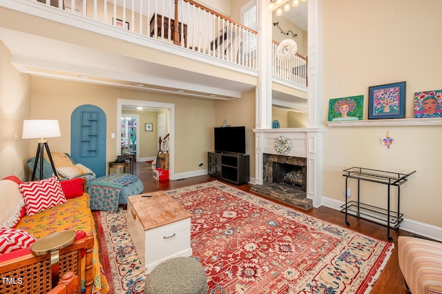 6035 Sentinel Dr, Raleigh, NC 27609 - living area featuring wood finished floors, a stone fireplace, a towering ceiling, and baseboards