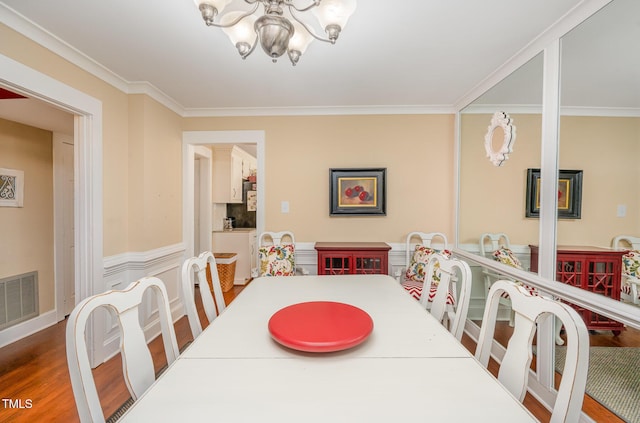 6035 Sentinel Dr, Raleigh, NC 27609 - dining area featuring a chandelier, ornamental molding, and wood finished floors