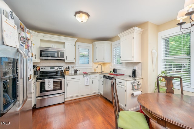 6035 Sentinel Dr, Raleigh, NC 27609 - kitchen featuring appliances with stainless steel finishes, a sink, backsplash, and white cabinets