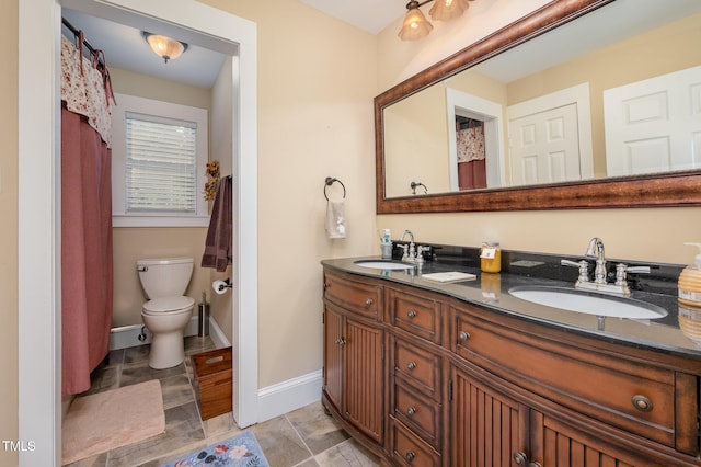 6035 Sentinel Dr, Raleigh, NC 27609 - bathroom with double vanity, toilet, and baseboards