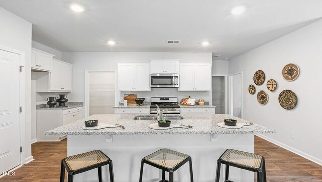 2132 Monk Dr, Haw River, NC 27258 - kitchen with stainless steel appliances, a sink, a breakfast bar, white cabinets, and recessed lighting