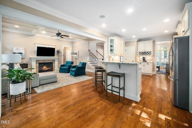 3748 Westbury Lake Dr, Raleigh, NC 27603 - kitchen with freestanding refrigerator, a kitchen breakfast bar, a glass covered fireplace, a peninsula, and light stone countertops