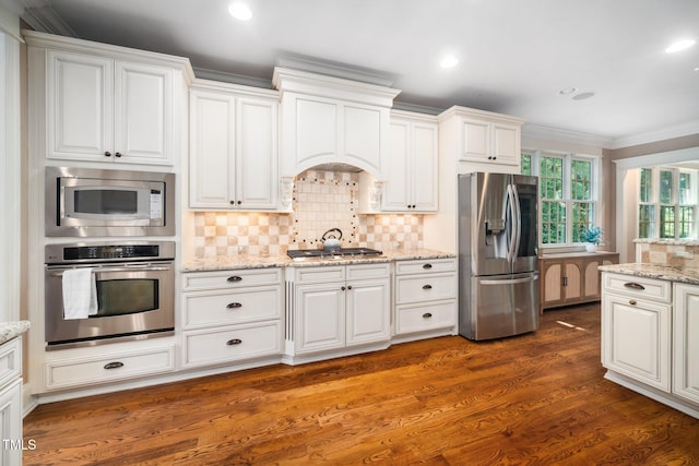 3748 Westbury Lake Dr, Raleigh, NC 27603 - kitchen featuring appliances with stainless steel finishes, crown molding, white cabinetry, decorative backsplash, and dark wood-style flooring