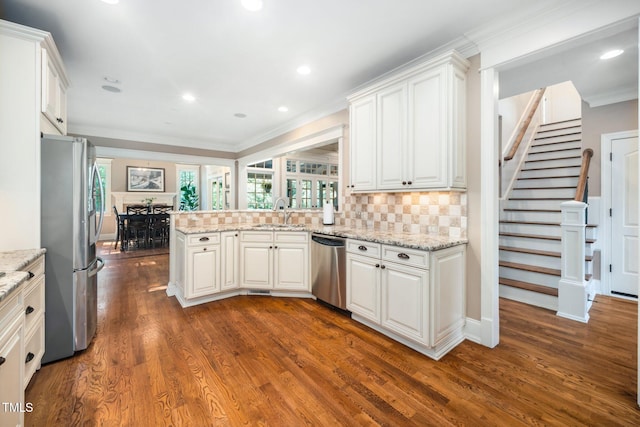3748 Westbury Lake Dr, Raleigh, NC 27603 - kitchen with appliances with stainless steel finishes, a peninsula, healthy amount of natural light, dark wood finished floors, and ornamental molding