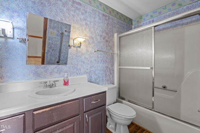 5437 Grasshopper Rd, Raleigh, NC 27610 - bathroom featuring wallpapered walls, vanity, bath / shower combo with glass door, toilet, and wood finished floors