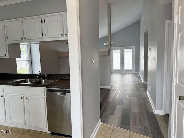5071 Avenida Del Sol Dr, Raleigh, NC 27616 - kitchen featuring stainless steel dishwasher, a sink, dark countertops, vaulted ceiling, and white cabinets