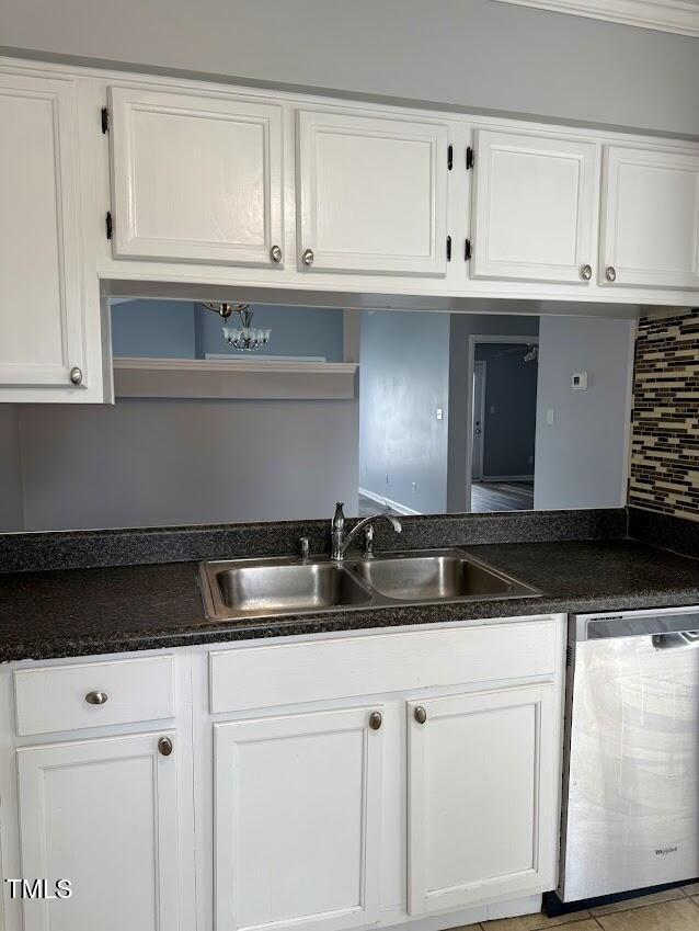 5071 Avenida Del Sol Dr, Raleigh, NC 27616 - kitchen with stainless steel dishwasher, white cabinets, a sink, dark countertops, and decorative backsplash