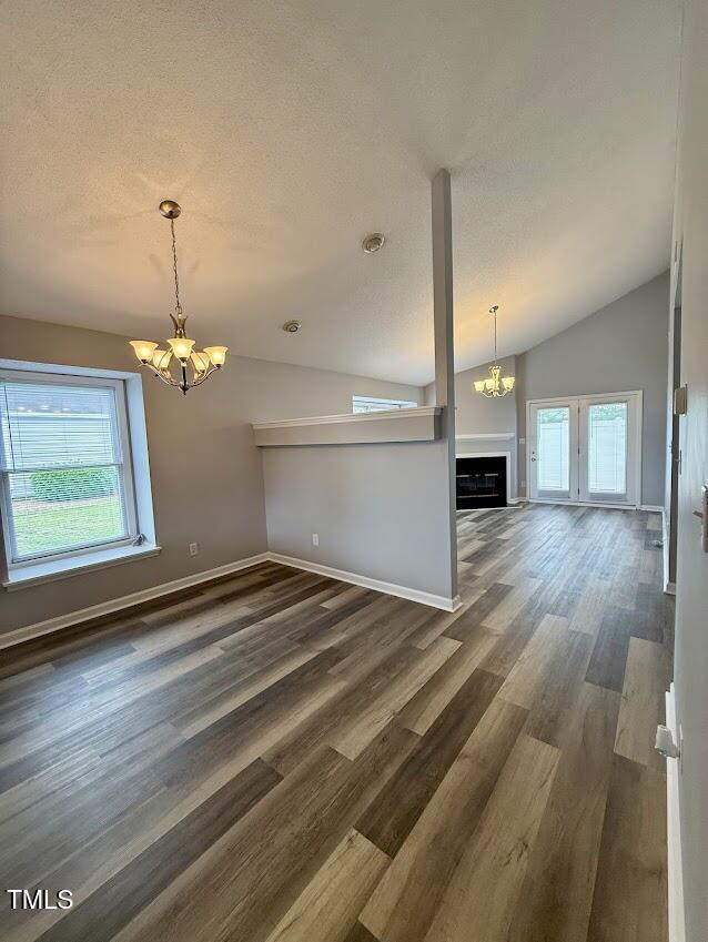 5071 Avenida Del Sol Dr, Raleigh, NC 27616 - unfurnished living room with a chandelier, plenty of natural light, vaulted ceiling, a fireplace, and a textured ceiling