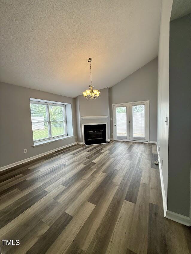 5071 Avenida Del Sol Dr, Raleigh, NC 27616 - unfurnished living room with dark wood-style flooring, baseboards, a chandelier, a textured ceiling, and a fireplace
