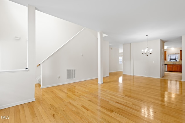 1405 Merrilow Ct, Wake Forest, NC 27587 - unfurnished living room featuring a chandelier, light wood-type flooring, stairs, baseboards, and a sink