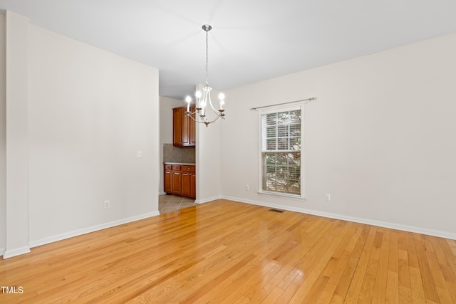 1405 Merrilow Ct, Wake Forest, NC 27587 - spare room featuring a chandelier, light wood finished floors, and baseboards
