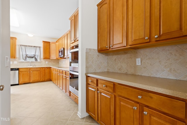1405 Merrilow Ct, Wake Forest, NC 27587 - kitchen featuring appliances with stainless steel finishes, a sink, light countertops, brown cabinets, and decorative backsplash