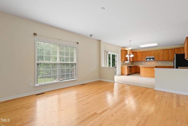 1405 Merrilow Ct, Wake Forest, NC 27587 - unfurnished living room featuring light wood-type flooring, baseboards, and a chandelier